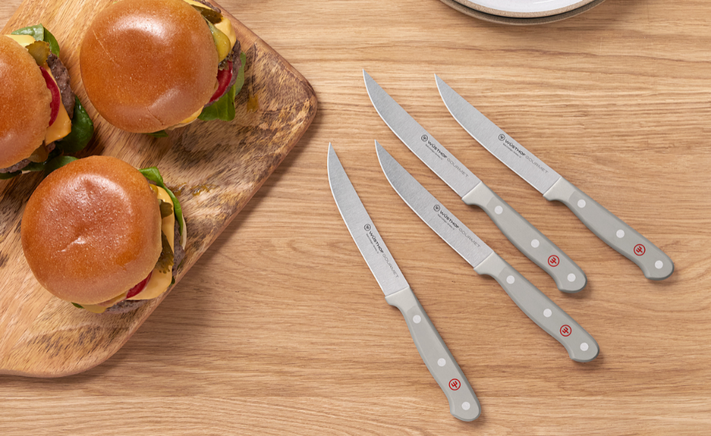 four gourmet steak knives near burgers and condiments