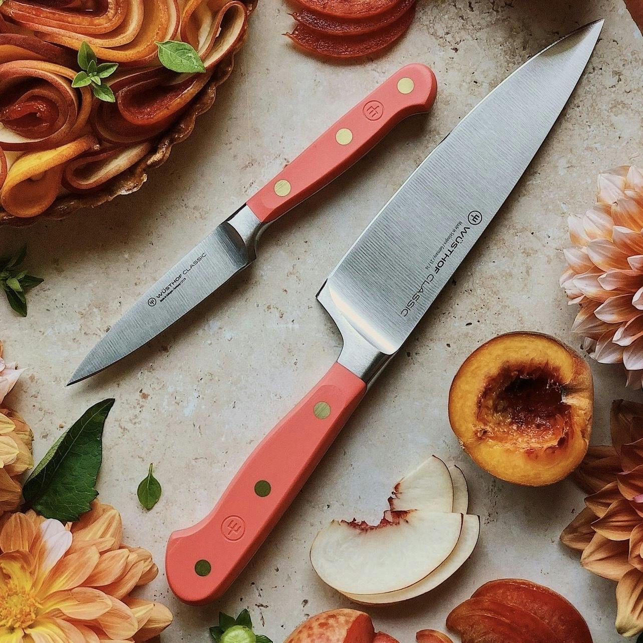 Coral Peach knives next to flowers, peaches and apple slices