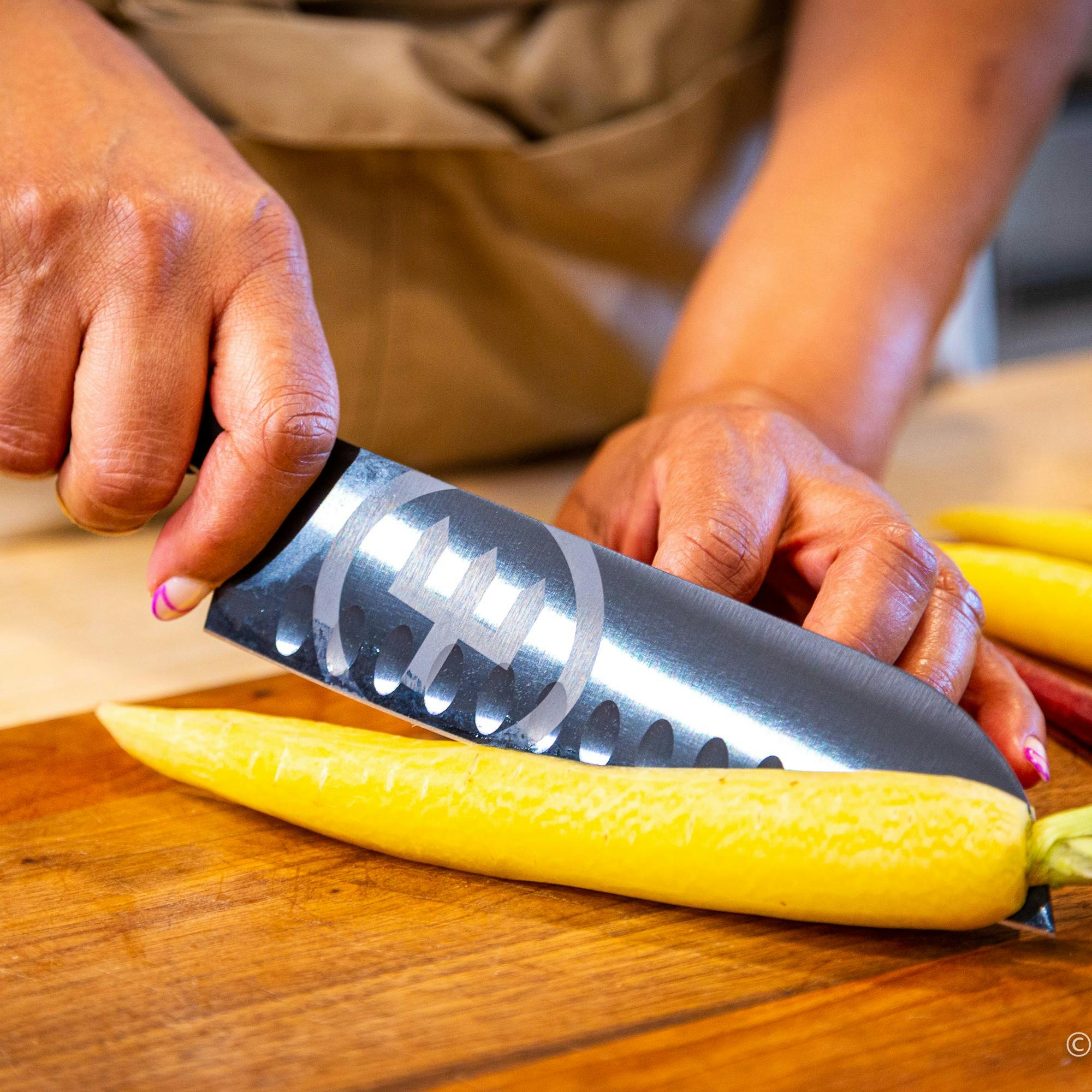 Chef Elle Simone Scott cutting a yellow carrot with a WUSTHOF Performer Santoku knife