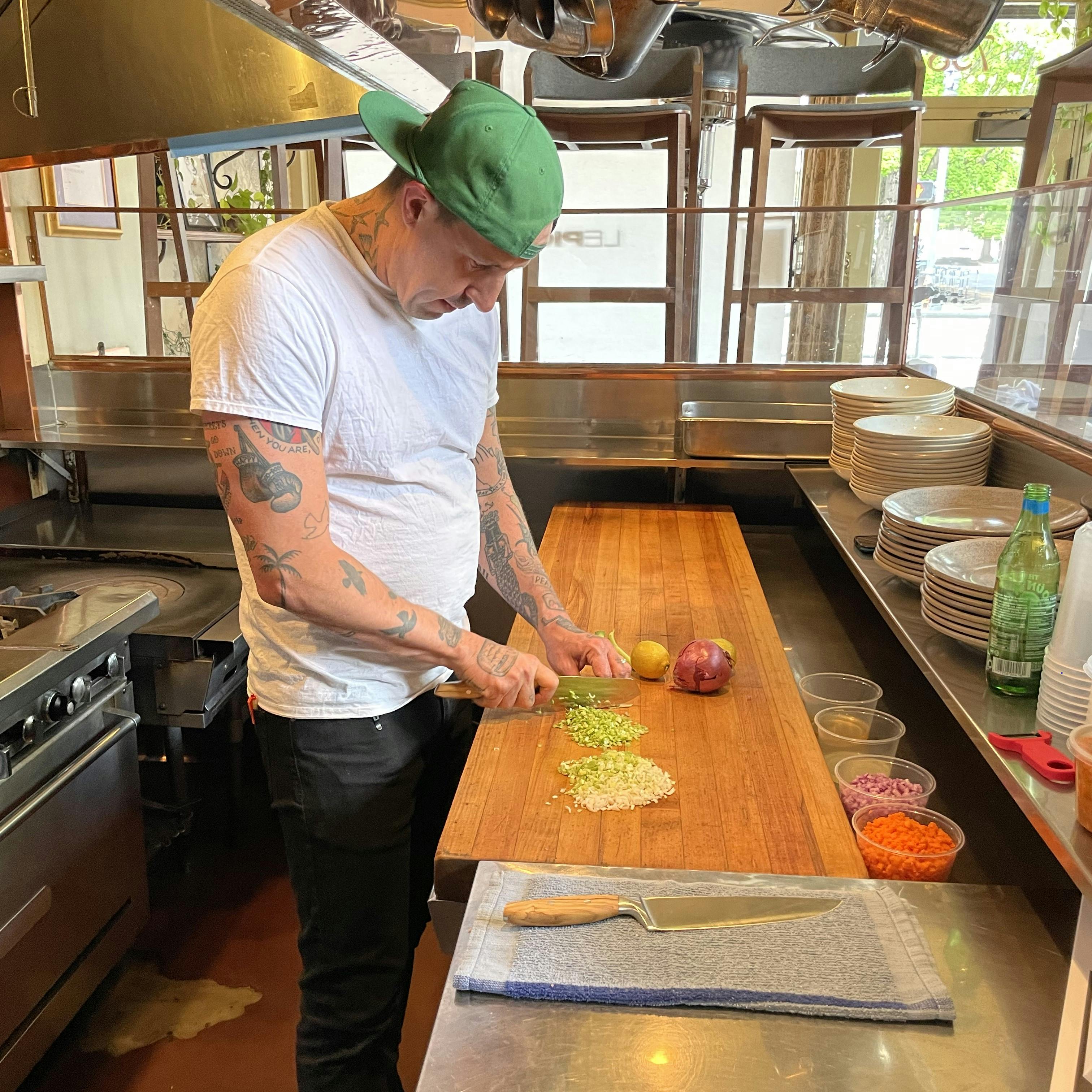 Chef Gabriel Rucker chopping vegetables with a WÜSTHOF Amici Santoku knife