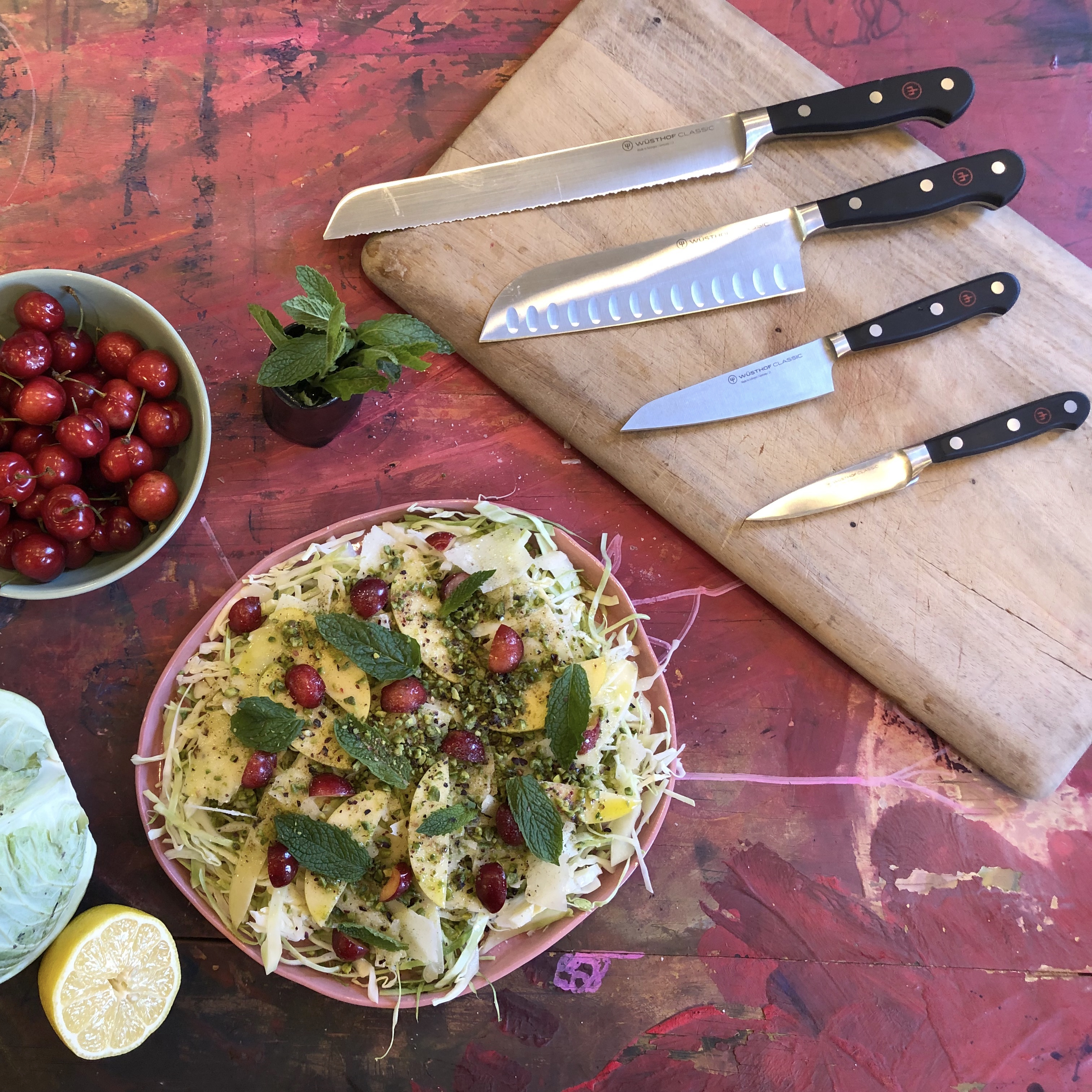 Cabbage salad plated with four WÜSTHOF knives arranged on a cutting board.