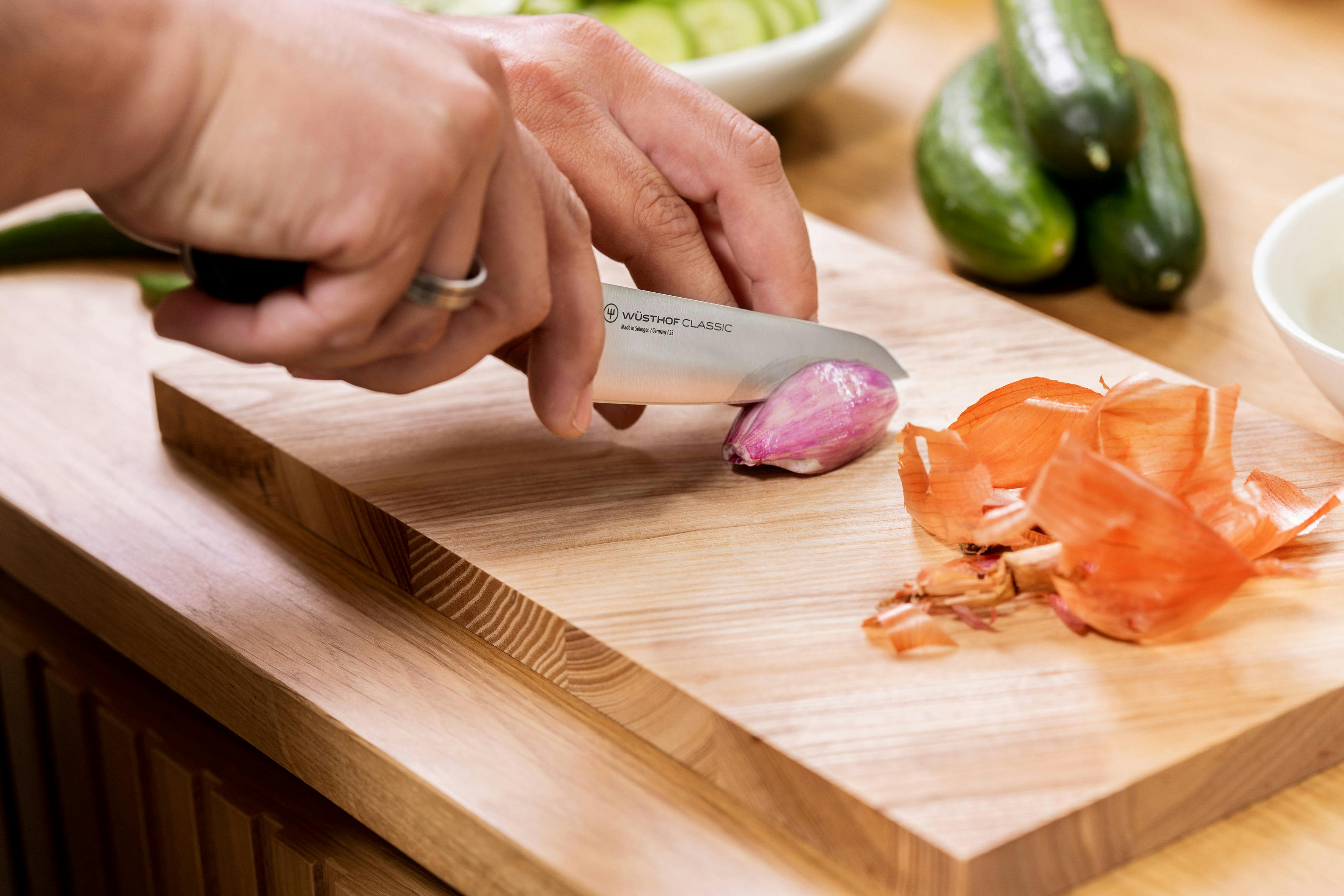 Close up view of asian utility knife cutting shallot