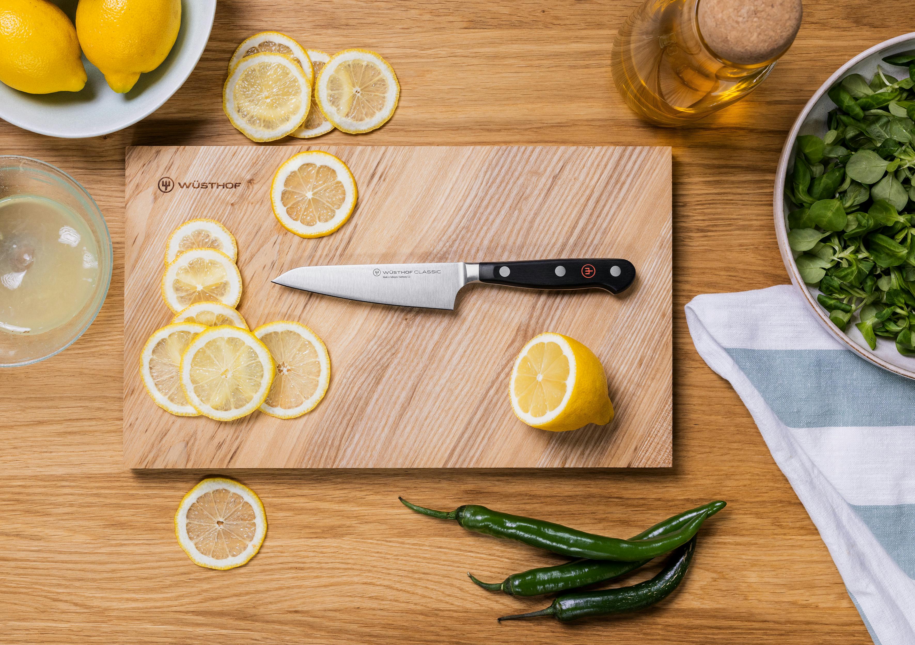 flat lay view of asian utility knife near lemons and peppers
